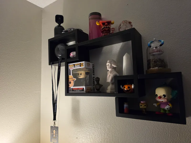 Display shelves with a model race car, collectibles, small busts, stones and candles.